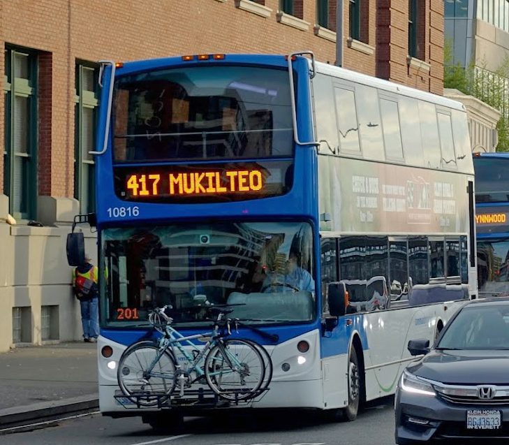  A double deck bus with 2 bike on a rack on the front of the bus
